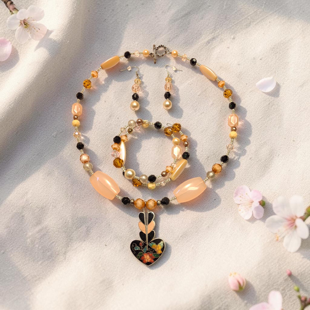 Peach Blossom Jewelry Set with cloisonne enamel heart pendant, peach barrel beads and amber crystals, photographed with cherry blossoms on linen