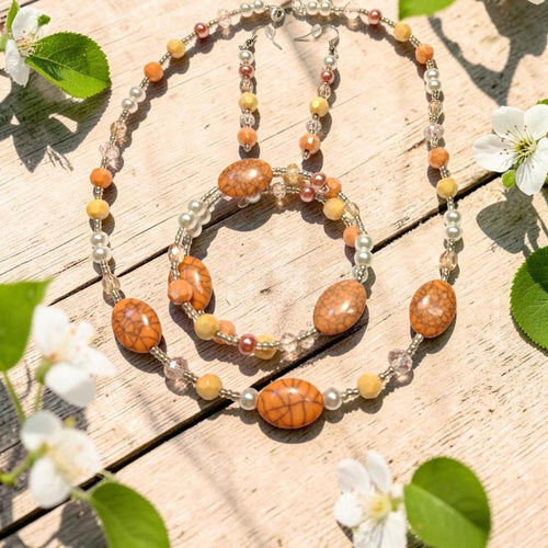 Crackling Rose Jewelry Set displayed on whitewashed wood with spring blossoms, featuring orange crackle agate ovals, yellow jade, blush pearls and clear crystals