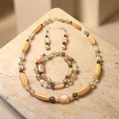 Dreaming in Pink Jewelry Set displayed on travertine stone, featuring peach mother-of-pearl ovals, smoky quartz, and freshwater pearls