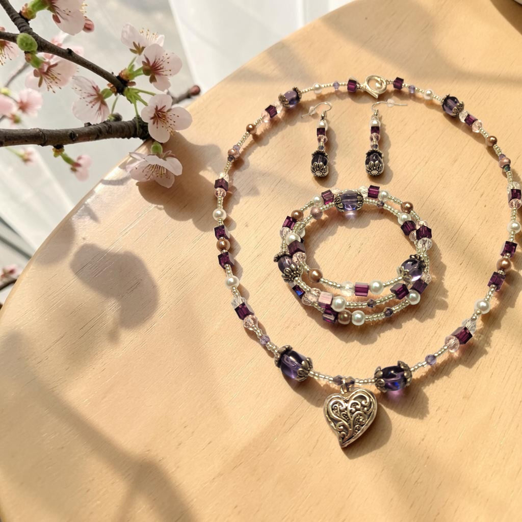 Amethyst Heart Jewelry Set with purple crystals, white pearls and ornate silver filigree heart pendant, photographed with cherry blossoms