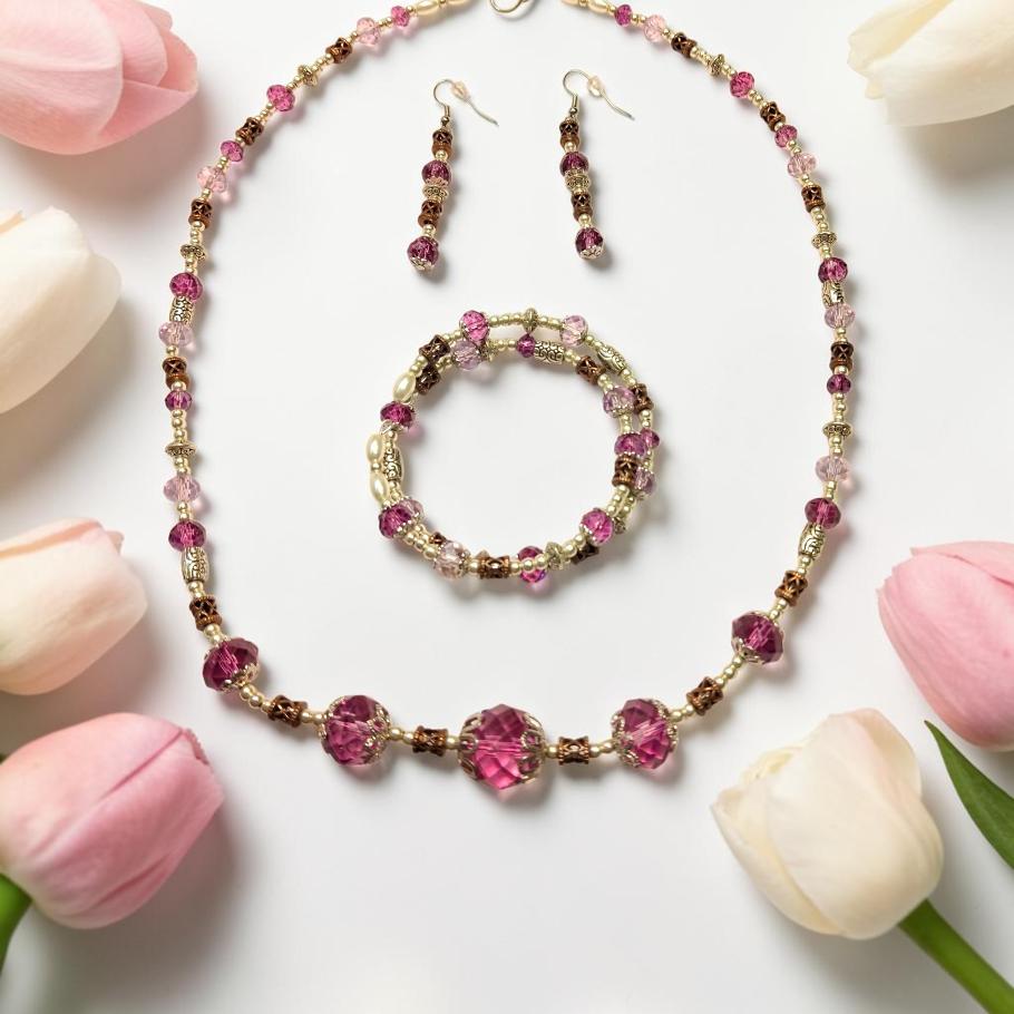 Fuchsia Garden Jewelry Set displayed with pink tulips, featuring bold fuchsia and magenta crystals with bronze filigree accents and cream pearls